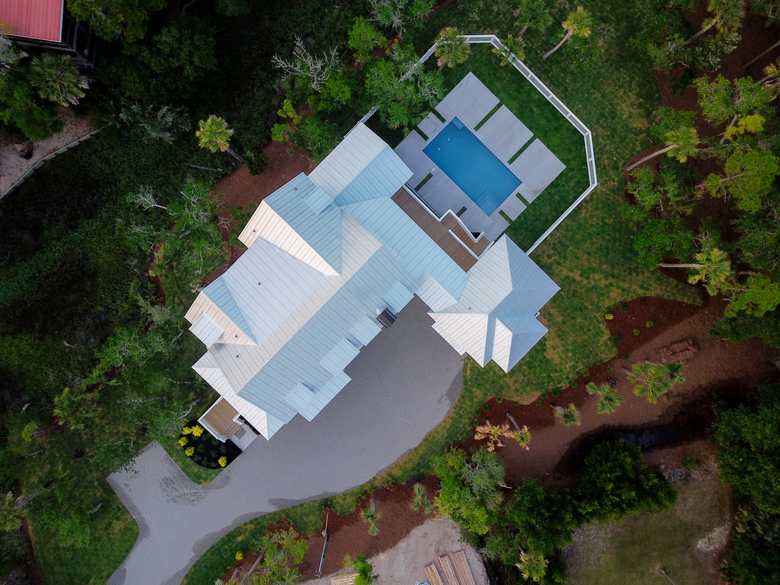 Drone photograph of a coastal home with a metal roof, pool, and landscaped grounds in Folly Beach, South Carolina